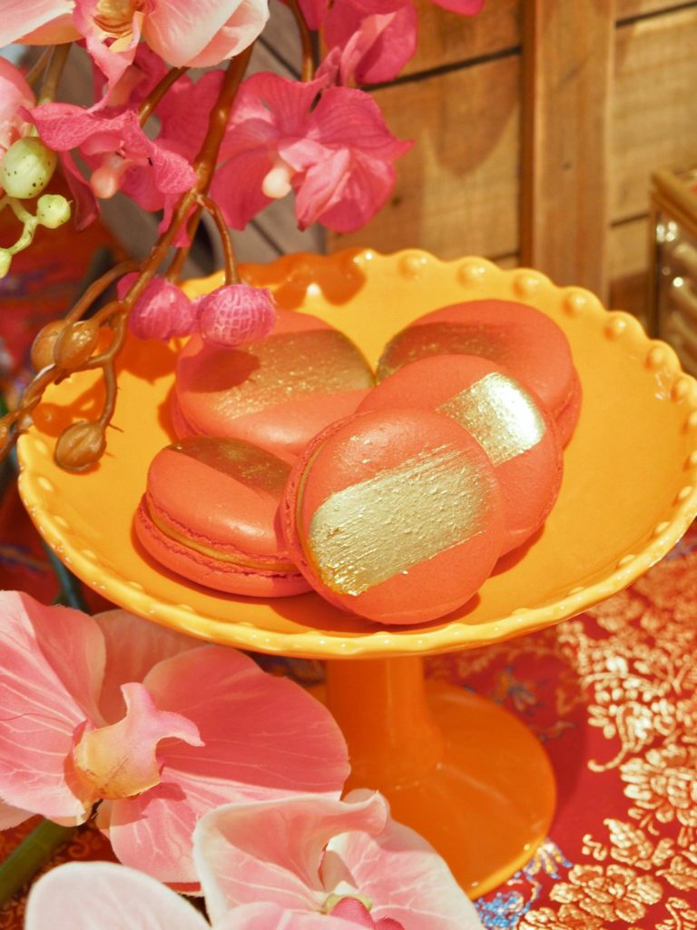 Red and gold macarons on a Singaporean themed dessert bar.