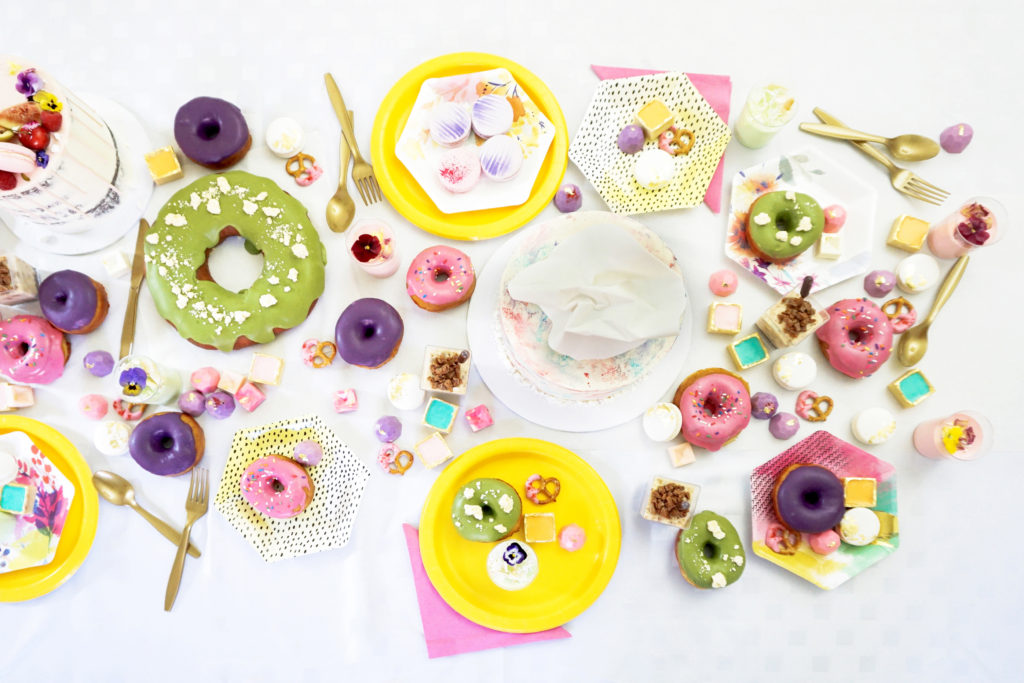 Donuts, mini chocs and macarons laid out with party plates